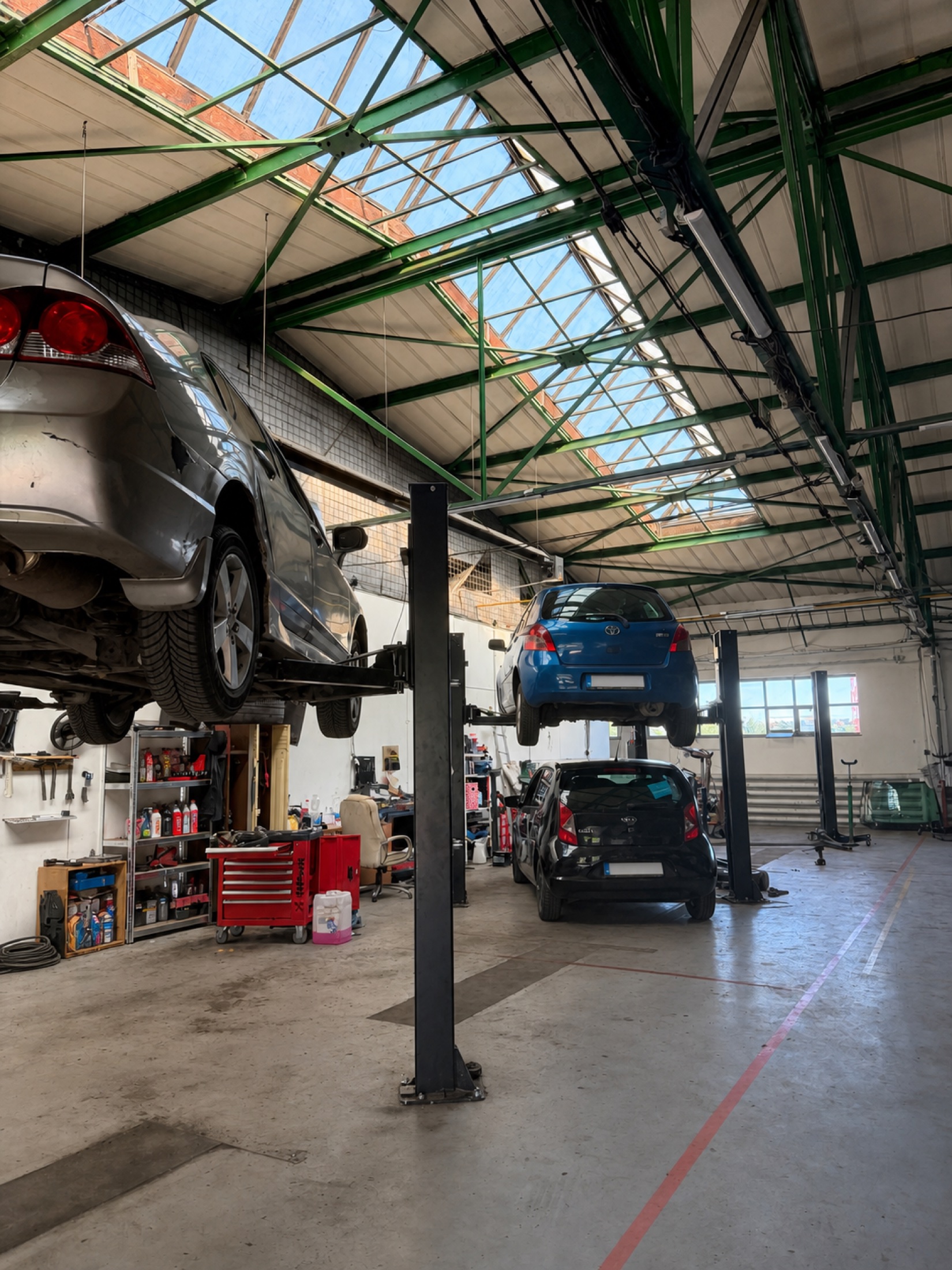 Automobily na zvedácích pod světlíkem dílny MotPro